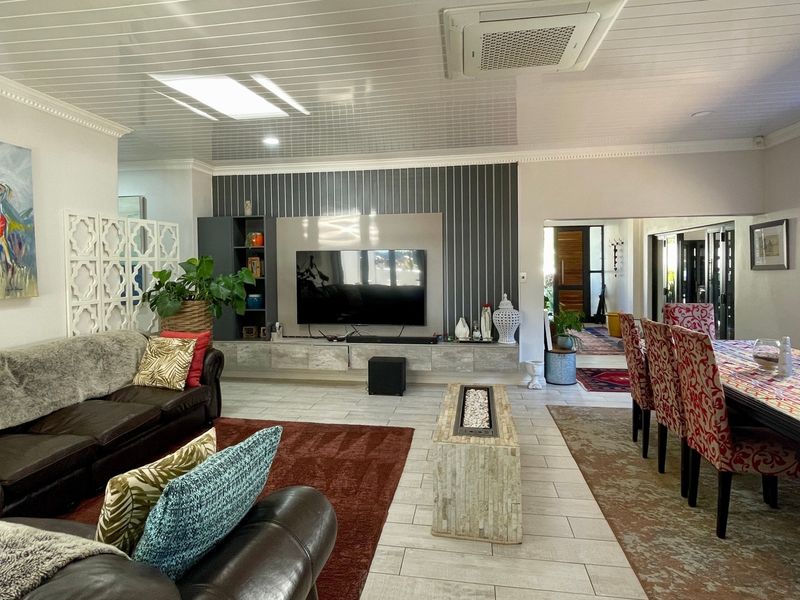 Spacious open-plan living and dining area featuring tiled floors, a modern built-in media wall, and integrated ducted air conditioning.