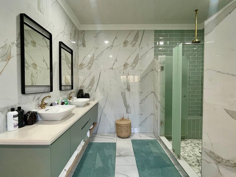 Modern bathroom featuring a double vanity with vessel sinks, brass fixtures, and a spacious walk-in shower with stylish marble and subway tile finishes.