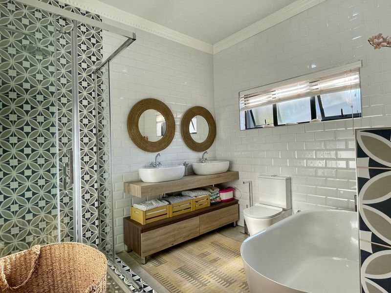 Modern bathroom featuring a double vanity with vessel sinks, a walk-in shower with decorative tiling, a freestanding bathtub, and subway tile wall finishes.