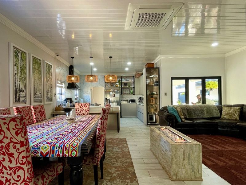 Spacious open-plan living and dining area featuring a built-in fireplace, tiled flooring, and a modern kitchen with integrated cabinetry and ducted air conditioning.