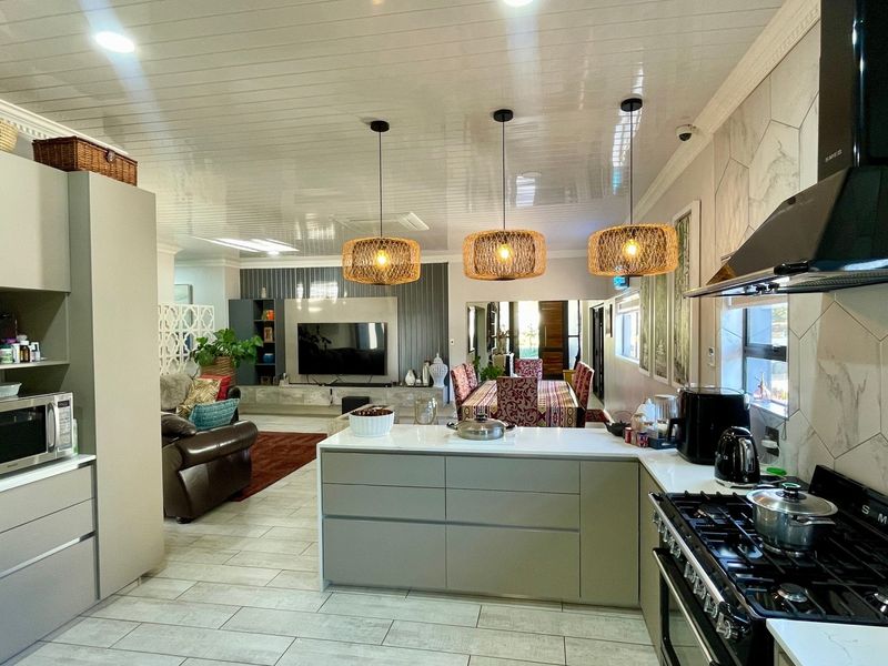 Spacious open-plan living area featuring a modern kitchen with a central island, gas stove, and contemporary cabinetry, flowing seamlessly into the dining and lounge spaces.