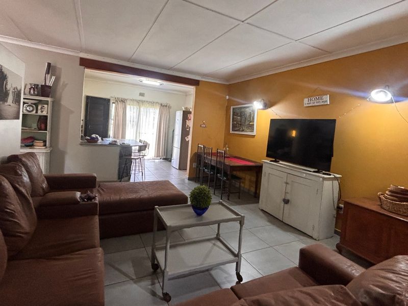 Open-plan living and dining area featuring tiled flooring, a drop ceiling, and a breakfast counter connecting to the kitchen space.