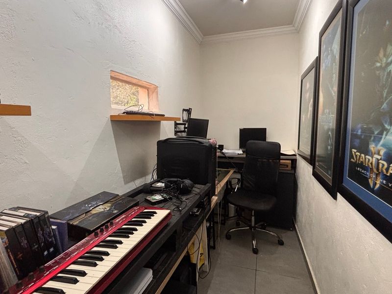 A compact home office or study space featuring tiled flooring, built-in shelving, and decorative cove cornicing.