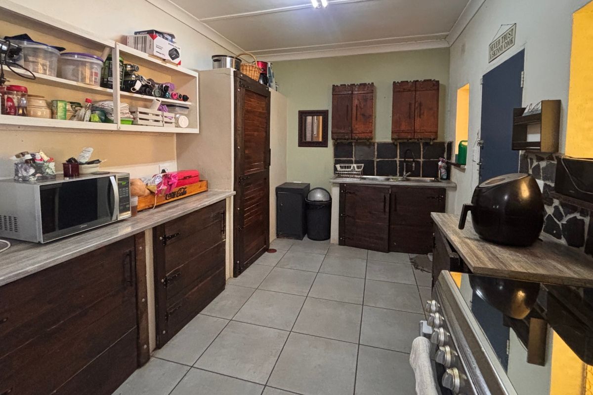 A functional kitchen featuring dark wood cabinetry, laminate countertops, tiled backsplash, and ceramic flooring, offering potential for a modern cosmetic update.