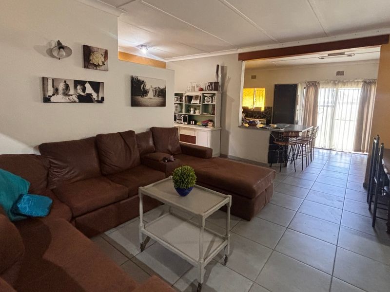 Spacious open-plan living and dining area featuring tiled flooring, a breakfast bar, and direct access to the exterior through sliding glass doors.