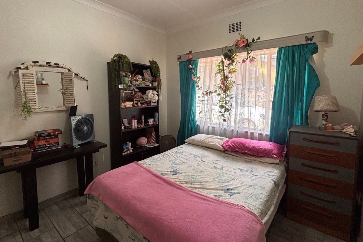 A functional bedroom featuring tiled flooring, cove cornicing, and a window with built-in curtain rail.