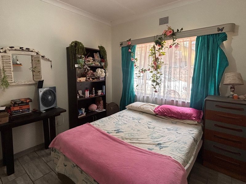 A functional bedroom featuring tiled flooring, cove cornicing, and a window with built-in curtain rail.