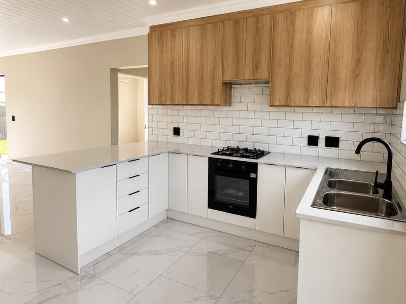 Modern kitchen featuring light wood upper cabinets, white lower cabinetry, stone countertops, subway tile backsplash, and integrated gas hob and oven.