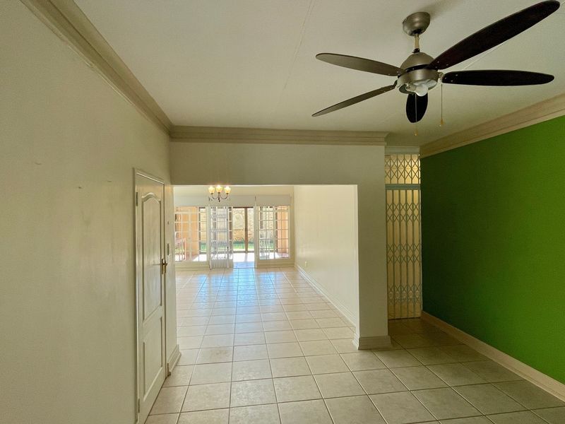 Spacious open-plan living area featuring ceramic tile flooring, a ceiling fan, and access to an outdoor patio through sliding glass doors.