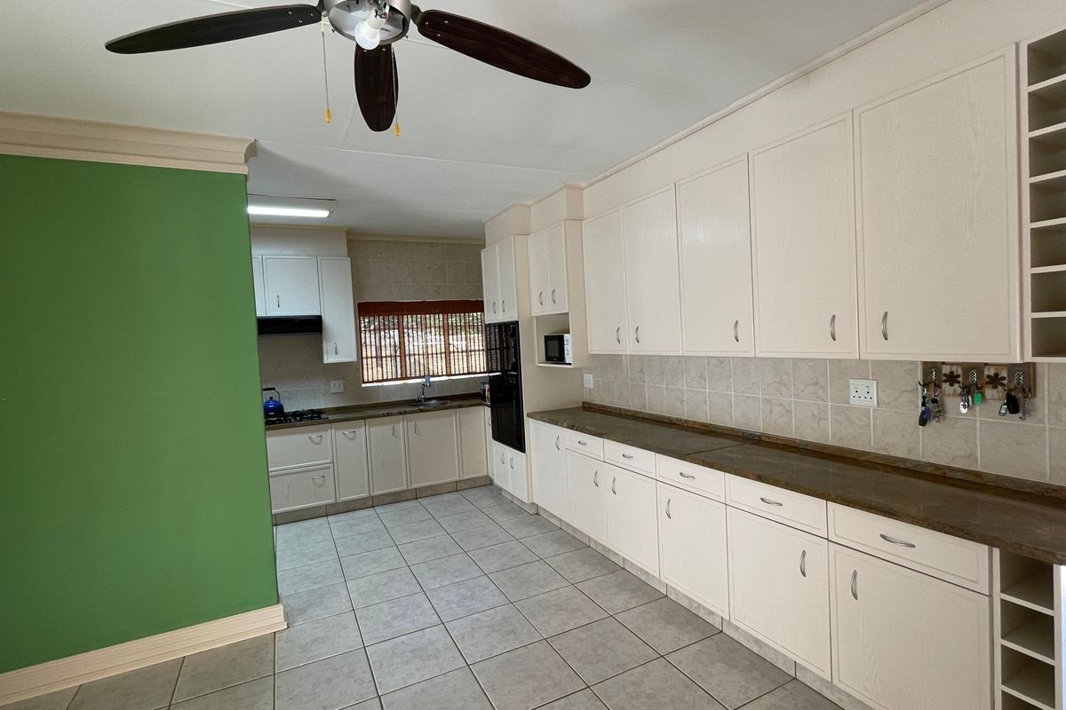 Spacious kitchen featuring extensive built-in cabinetry, laminate countertops, tiled flooring, and integrated appliances, offering a functional layout with ample storage space.