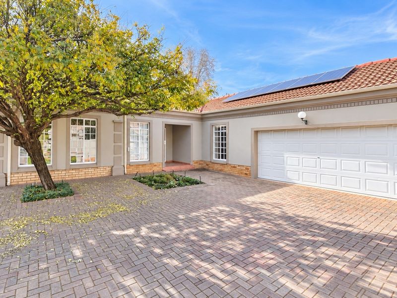 Front exterior view of a townhouse featuring a paved driveway, double garage, and solar panels installed on the tiled roof.