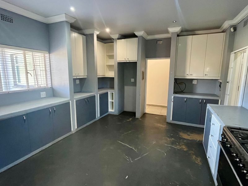 A spacious, empty kitchen featuring built-in cabinetry, laminate countertops, and a gas stove, offering a functional layout ready for updates.