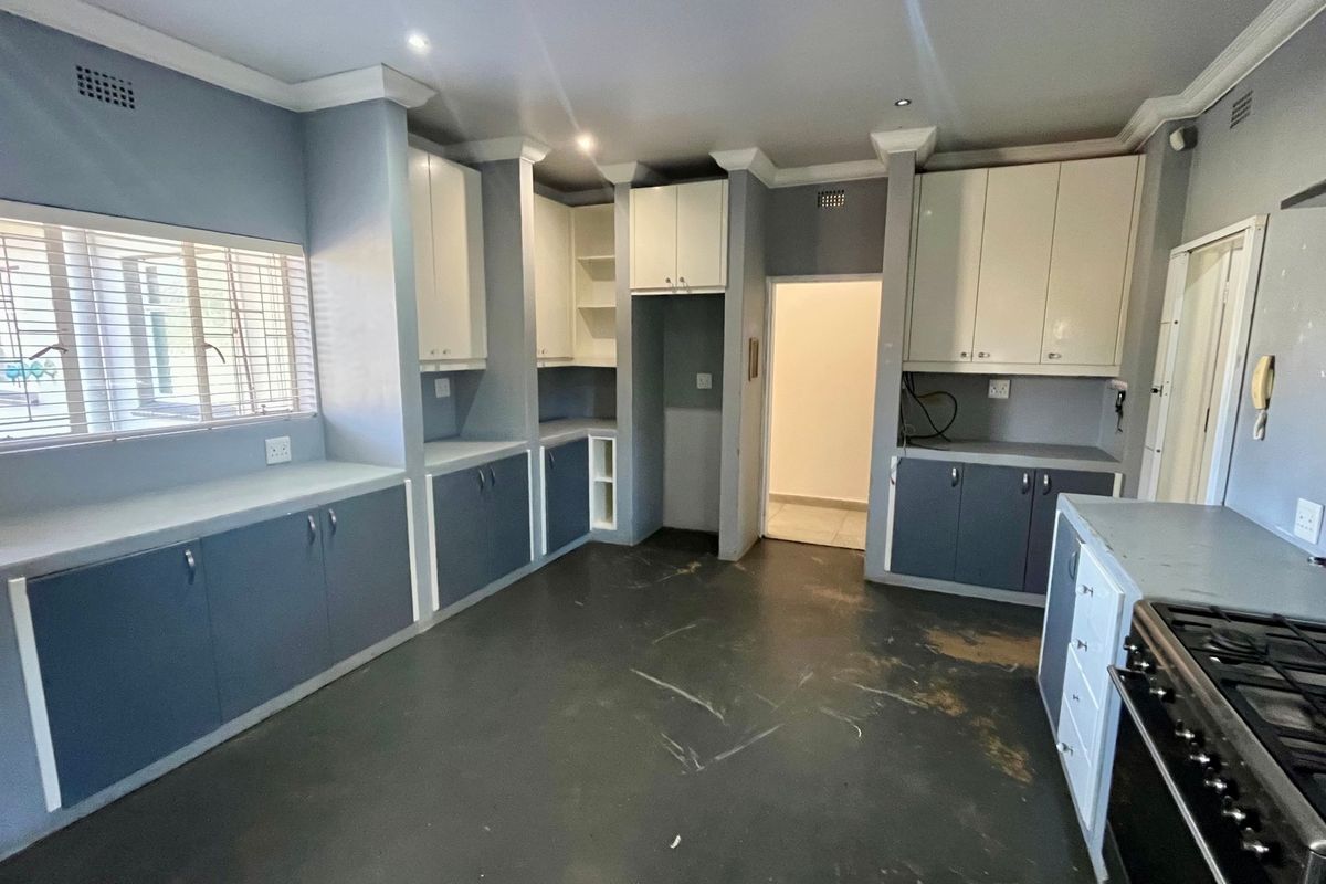 A spacious, empty kitchen featuring built-in cabinetry, laminate countertops, and a gas stove, offering a functional layout ready for updates.