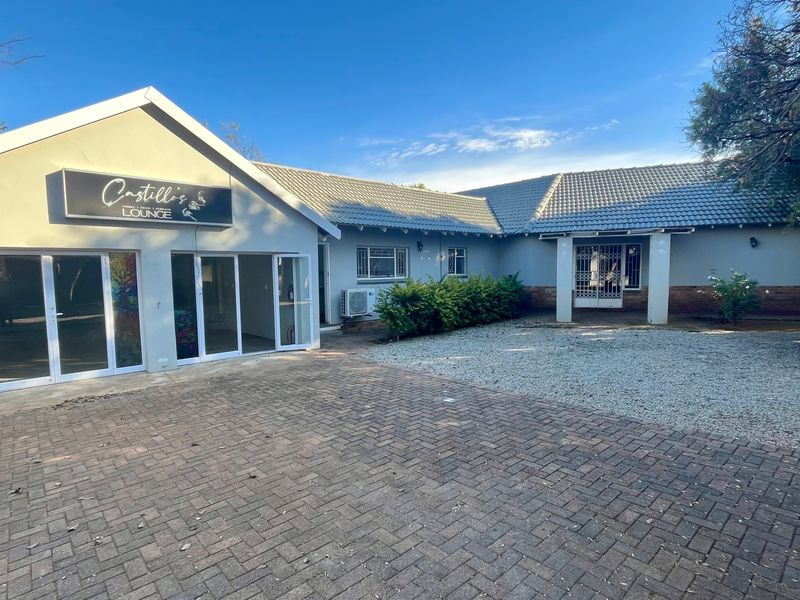 Front exterior view of the property featuring a paved driveway, tiled roof, and aluminium sliding doors leading into the main building structure.