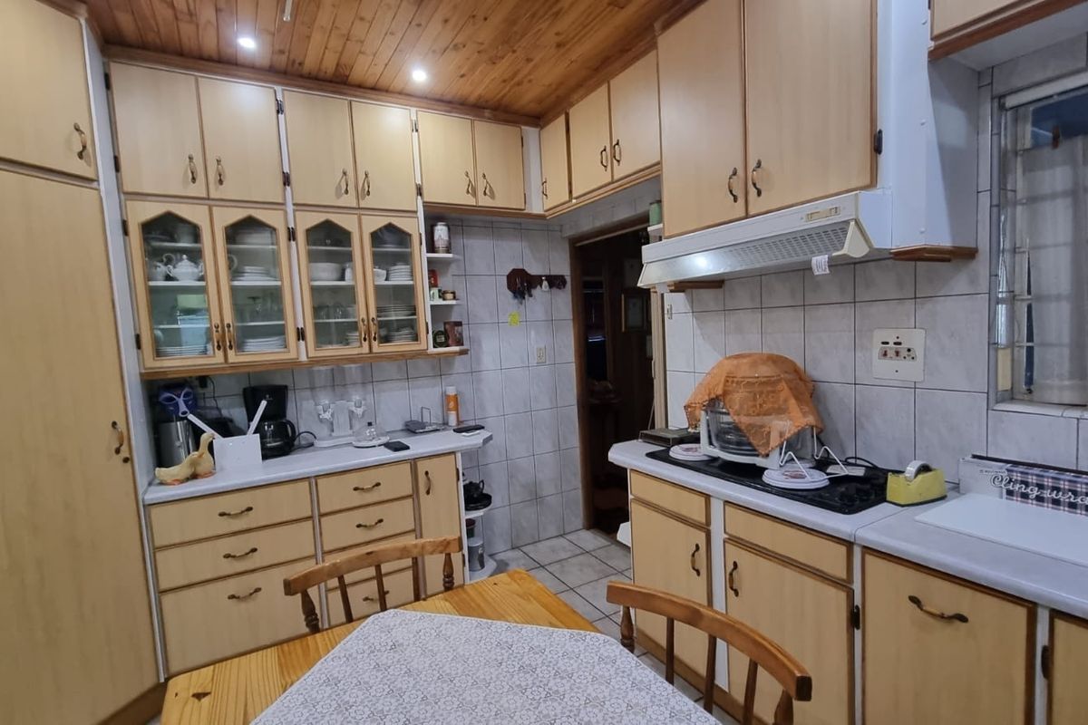 A functional kitchen featuring extensive built-in cabinetry, a timber ceiling, tiled backsplash, and a built-in hob with an extractor fan.