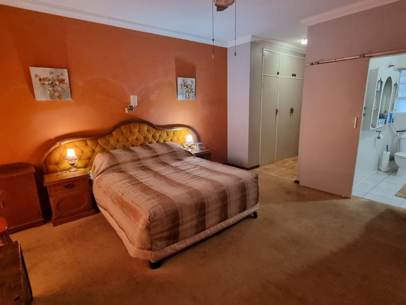Spacious bedroom featuring built-in cupboards and an adjoining en-suite bathroom with a sliding door entry.