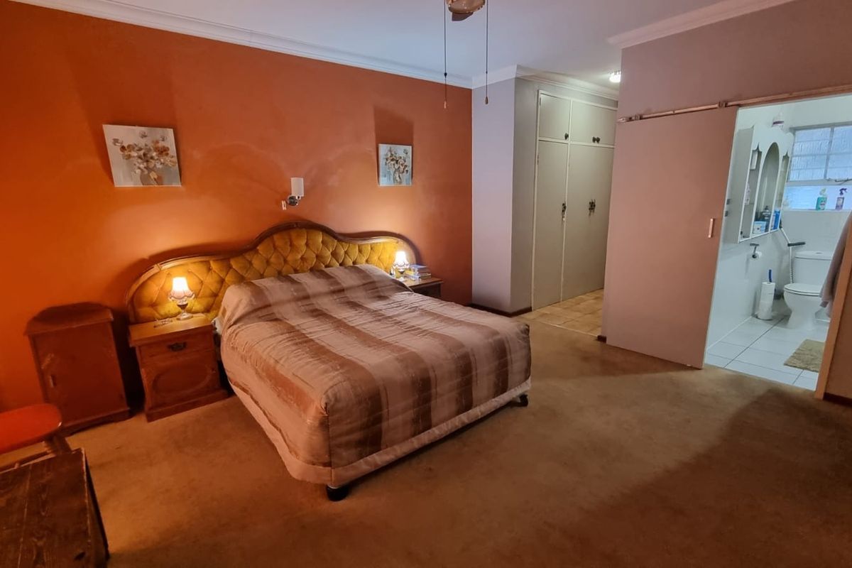 Spacious bedroom featuring built-in cupboards and an adjoining en-suite bathroom with a sliding door entry.