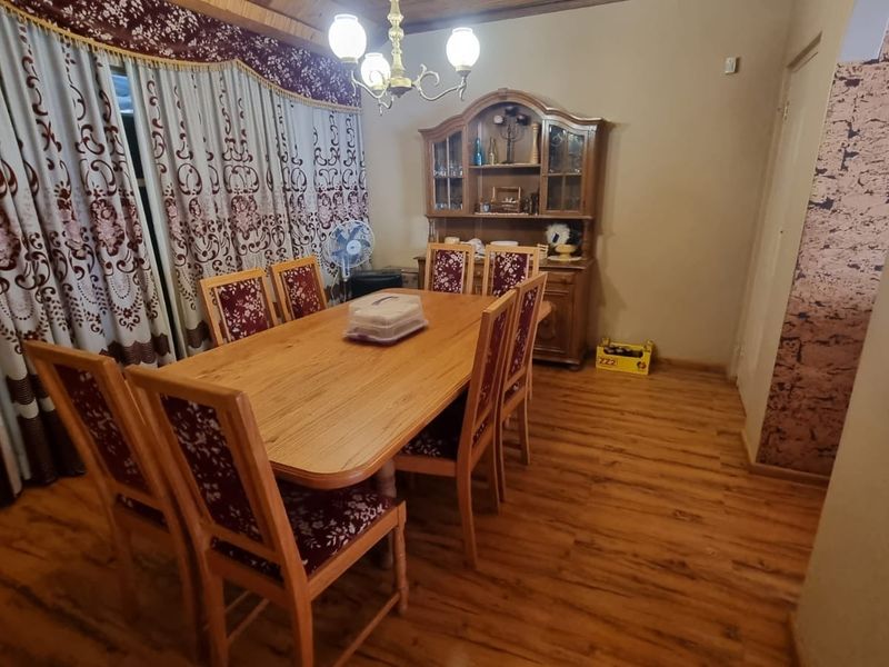 A dining room featuring laminate flooring, a timber ceiling, and a central chandelier, providing a traditional space for family meals.