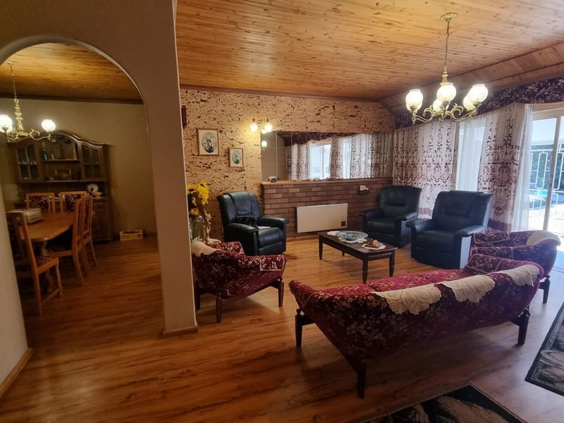 Open plan living and dining area featuring timber ceilings, brick accents, and direct access to the outdoor patio through sliding glass doors.