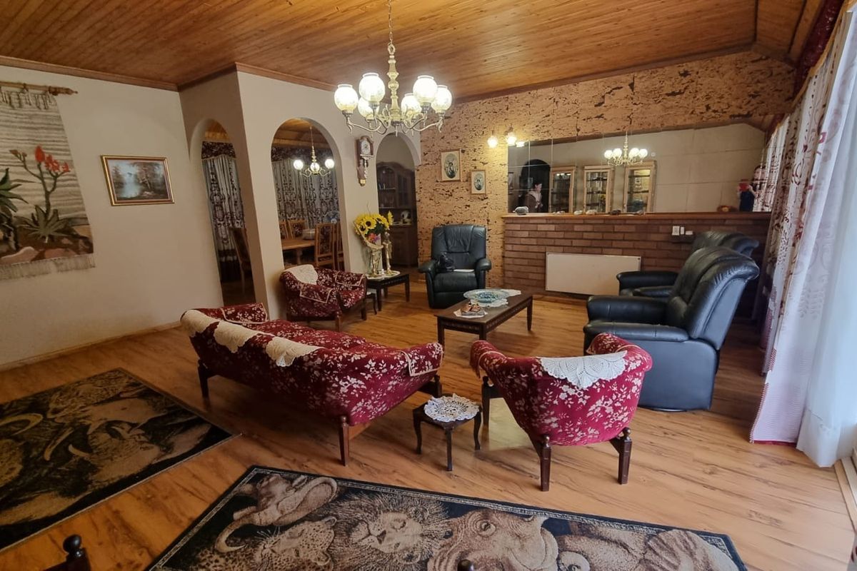 Spacious living room featuring a timber-clad ceiling, brick feature wall, and arched entryways leading to the dining area.