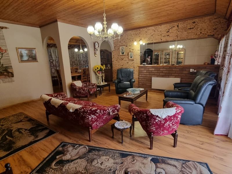 Spacious living room featuring a timber-clad ceiling, brick feature wall, and arched entryways leading to the dining area.