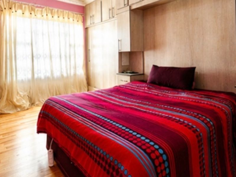 A bedroom featuring hardwood flooring and extensive built-in cabinetry with an integrated headboard design.