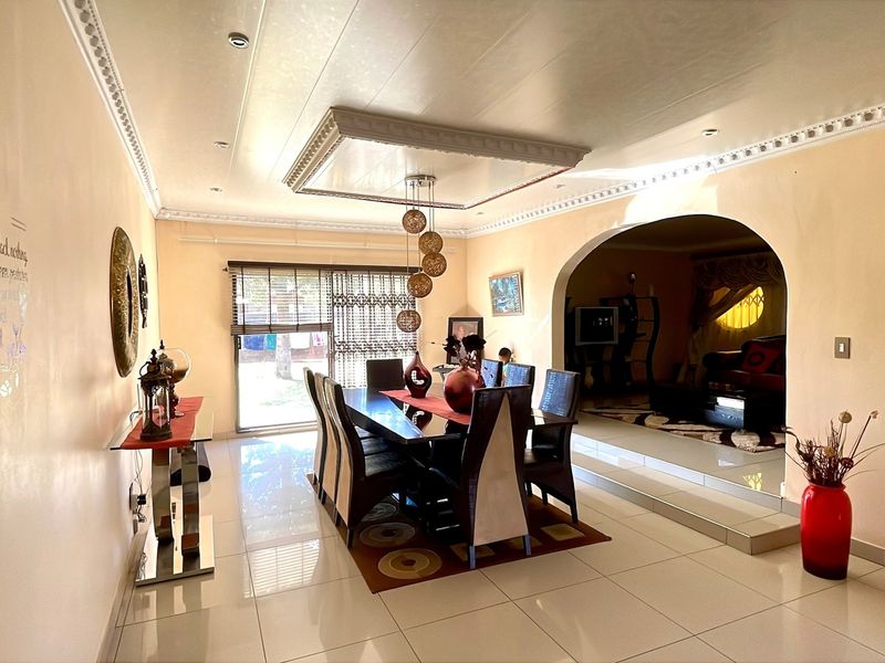 Spacious dining area featuring tiled floors, decorative ceiling molding, and a large archway leading to an adjacent living space.