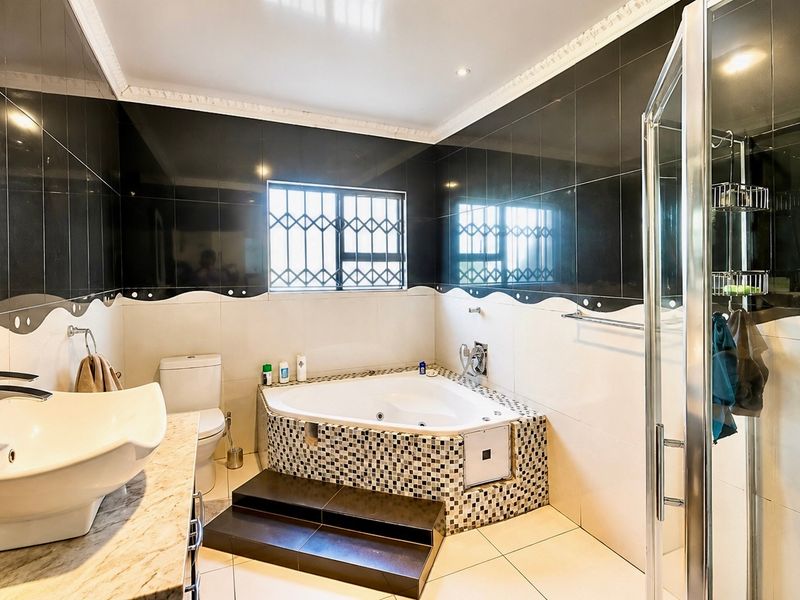 A spacious bathroom featuring a corner bathtub, separate shower enclosure, vanity basin, and tiled finishes throughout.