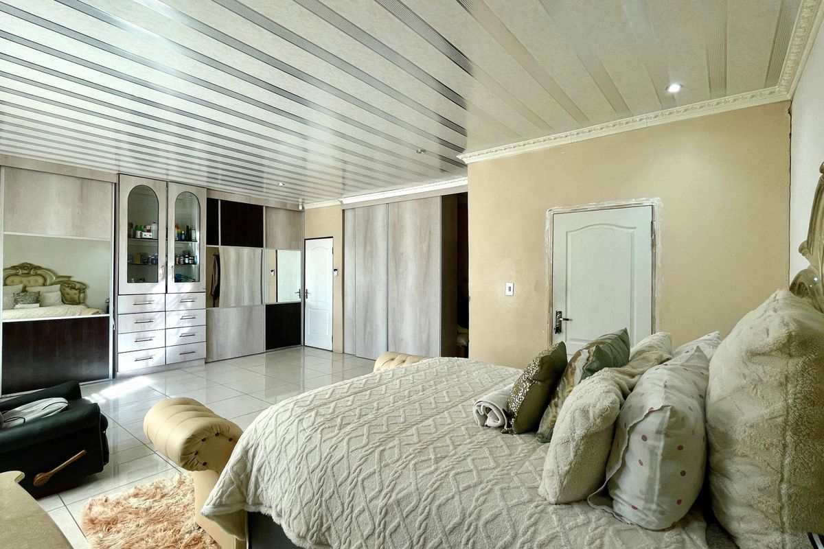 Spacious bedroom featuring extensive built-in cabinetry, tiled flooring, and a unique panelled ceiling design with recessed lighting.