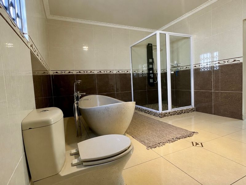 Spacious modern bathroom featuring a freestanding bathtub, a separate glass-enclosed shower, and neutral tiled finishes throughout.
