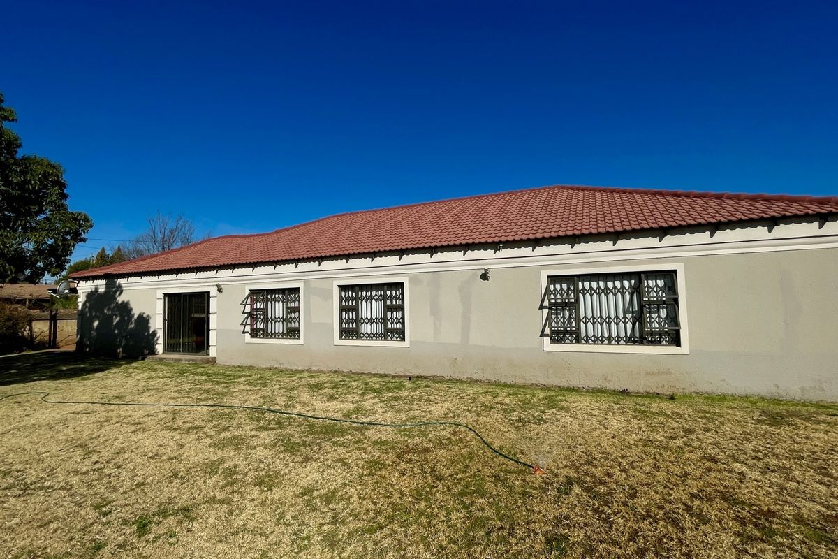 Rear view of the house featuring a tiled roof, security-fitted windows, and a sliding door leading to the backyard.