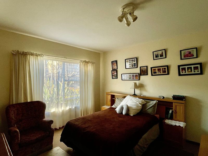 A bedroom featuring a built-in headboard and large window with natural light, offering a functional space with potential for modern updates.