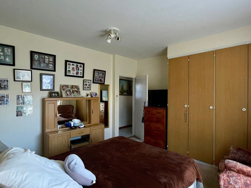 A bedroom featuring built-in wooden cupboards and a ceiling-mounted spotlight fixture, offering a functional space with potential for modern updates.