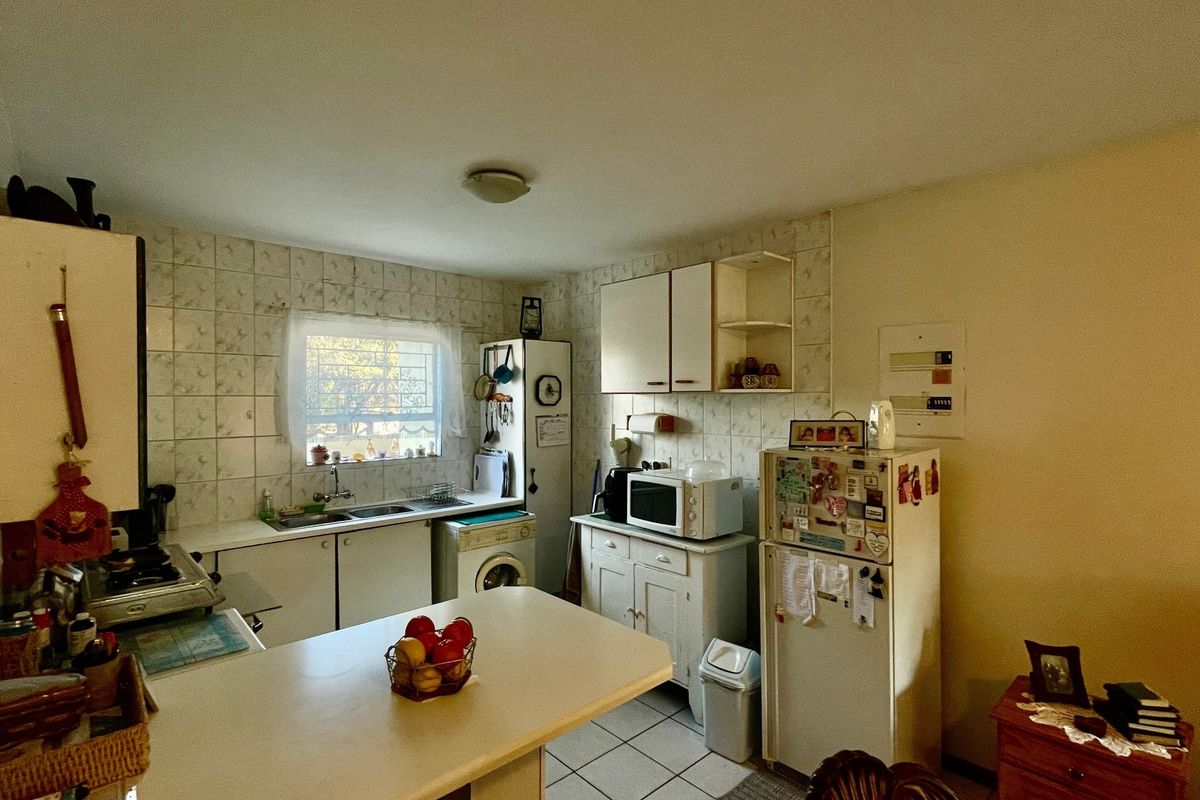 A functional kitchen featuring tiled backsplash, built-in cabinetry, and tiled flooring, offering a dated aesthetic with potential for modernization.