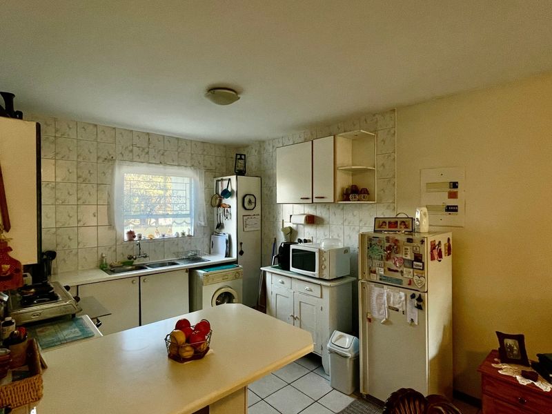 A functional kitchen featuring tiled backsplash, built-in cabinetry, and tiled flooring, offering a dated aesthetic with potential for modernization.