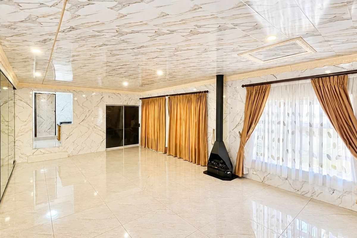 Spacious living area featuring marble-effect wall and ceiling finishes, tiled flooring, and a modern freestanding fireplace.