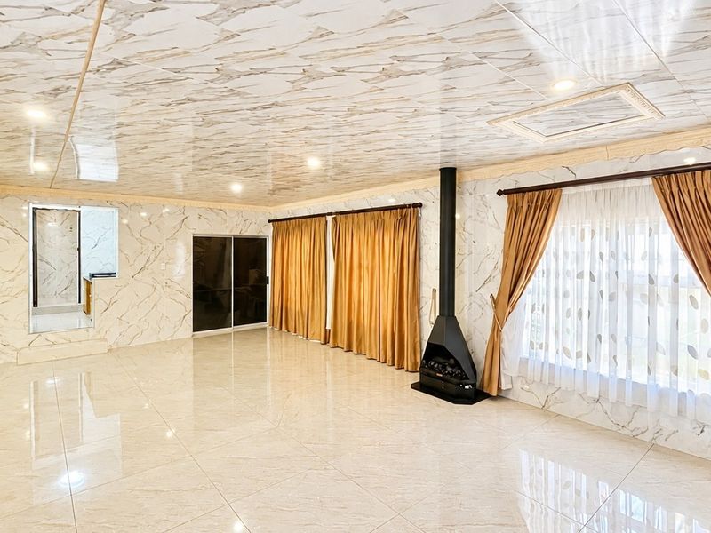 Spacious living area featuring marble-effect wall and ceiling finishes, tiled flooring, and a modern freestanding fireplace.