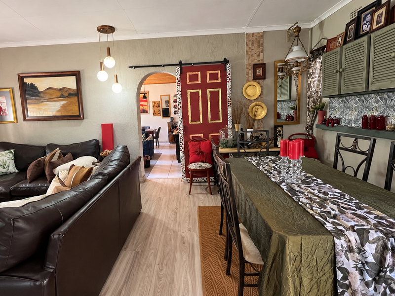 Open-plan living and dining area featuring laminate flooring, a distinctive arched doorway with a sliding barn door, and built-in wall cabinetry.