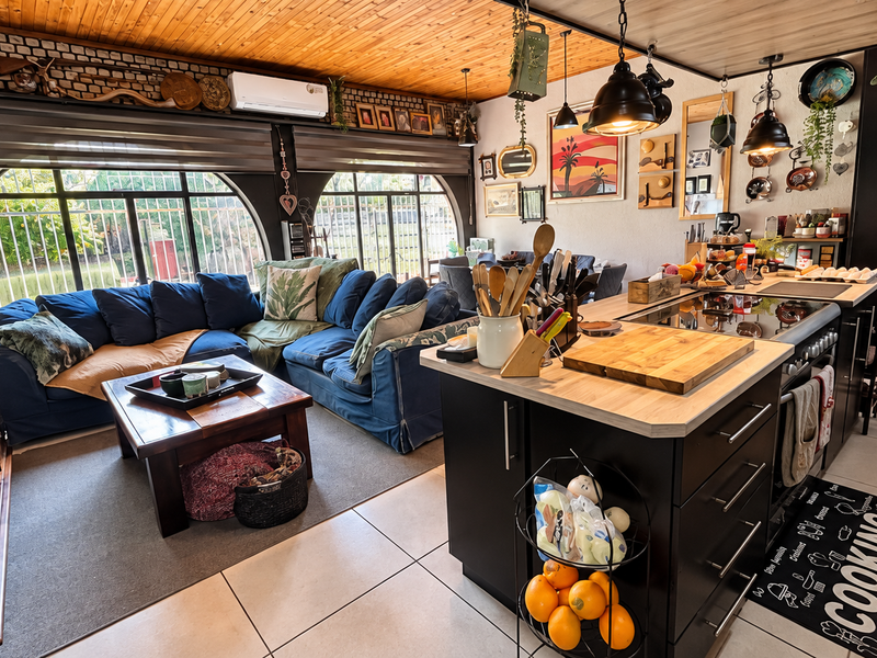 Spacious open-plan living and kitchen area featuring a central island, modern cabinetry, timber ceiling, and large arched windows overlooking the garden.