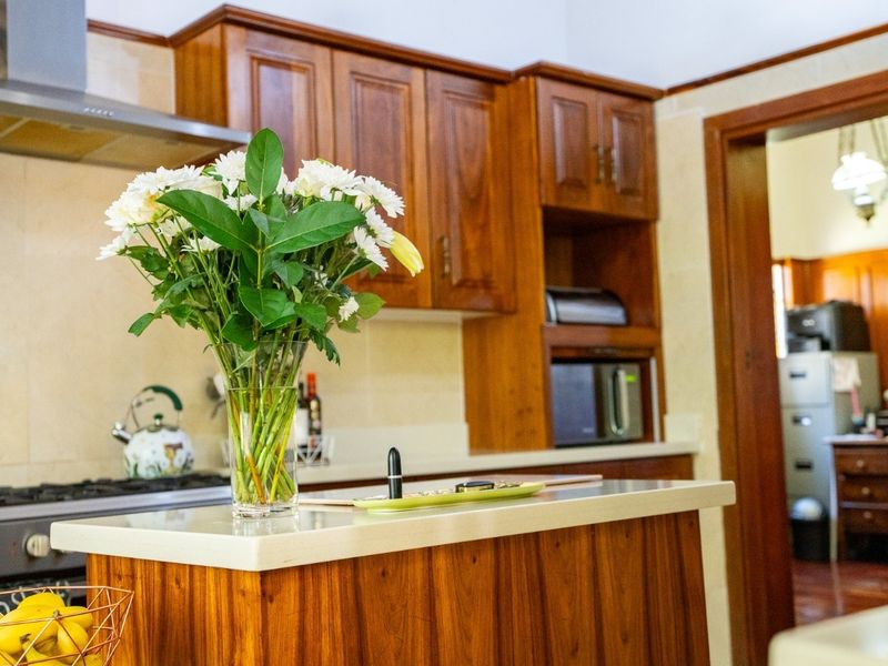 A well-maintained kitchen featuring warm wooden cabinetry, stone countertops, and integrated stainless steel appliances, offering a classic and functional cooking space.