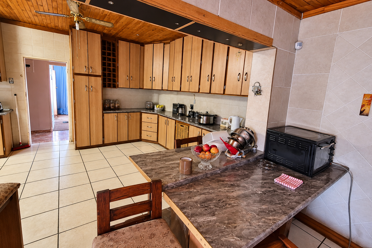 A functional kitchen featuring extensive wooden cabinetry, tiled flooring, and a breakfast bar, offering a traditional layout with ample storage space.