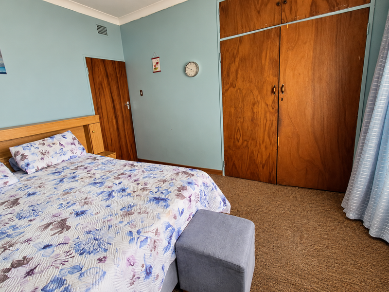 A bedroom featuring built-in wooden wardrobes, carpeted flooring, and light blue walls, offering a functional and traditional living space.