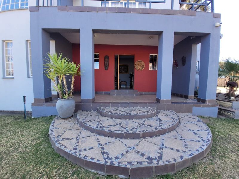 Front entrance featuring a covered porch with structural pillars and decorative tiled steps leading to the main doorway.
