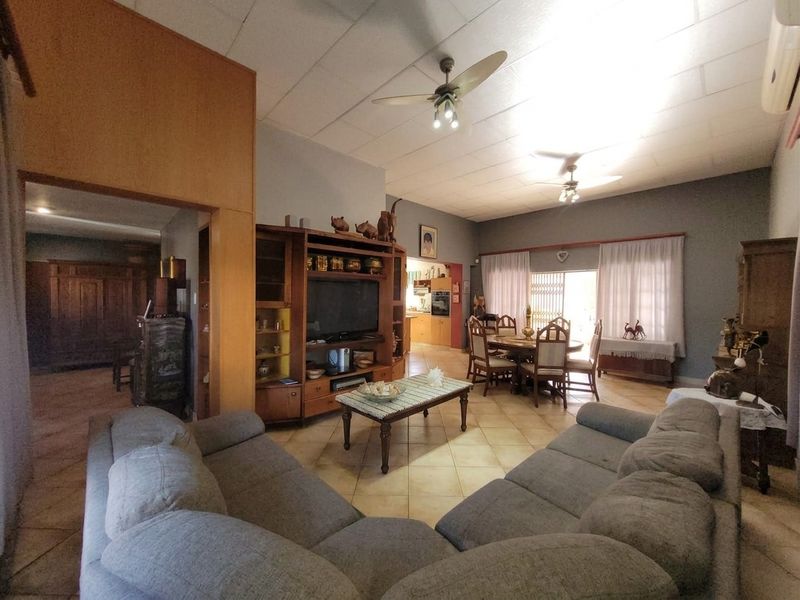 Spacious open-plan living and dining area featuring tiled flooring, ceiling fans, and direct access to the outdoor space through a sliding glass door.