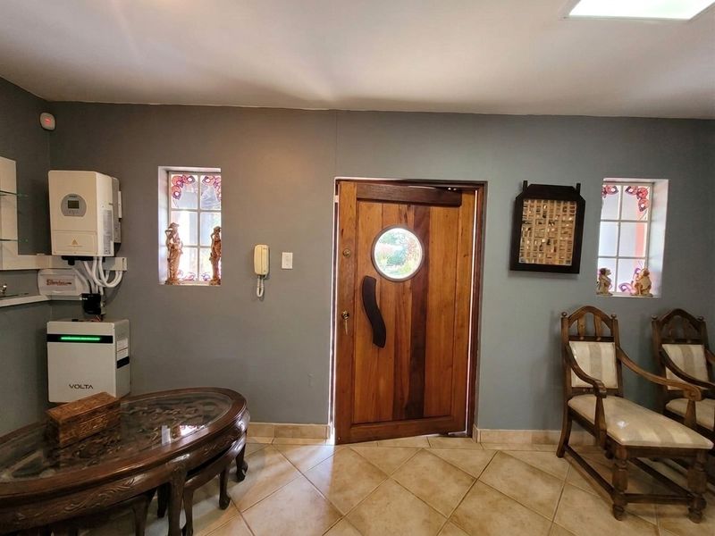 Welcoming entrance hall featuring a unique timber door with a porthole window, tiled flooring, and integrated power backup infrastructure.