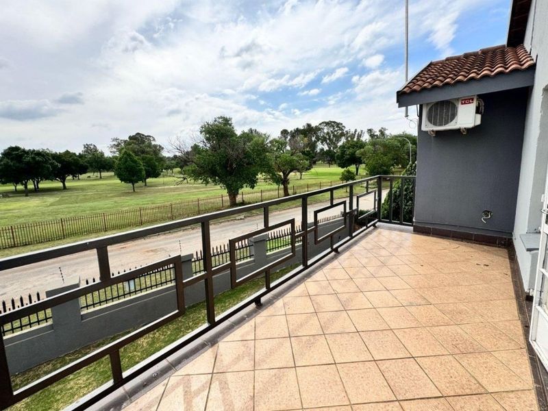 A spacious balcony featuring tiled flooring and a metal balustrade, offering an elevated view over the surrounding landscape.