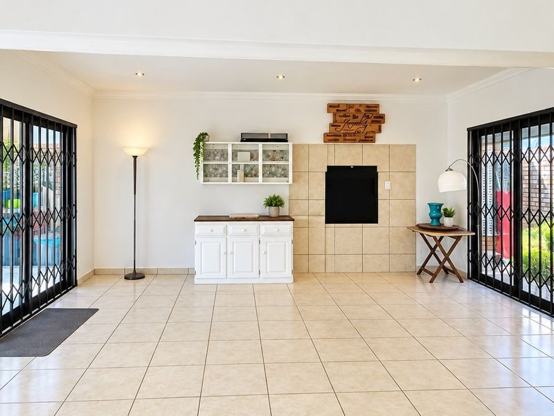 Spacious living area featuring tiled flooring, a built-in fireplace, and large sliding glass doors with security gates providing access to the outdoor space.