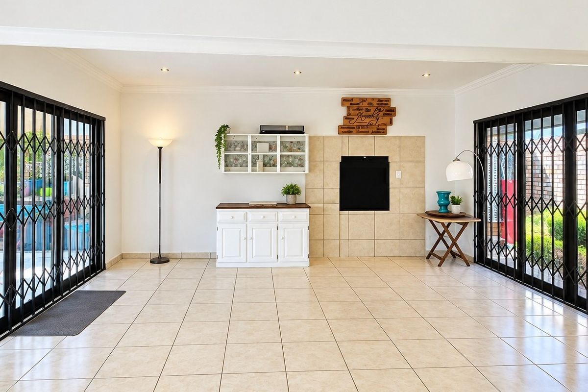 Spacious living area featuring tiled flooring, a built-in fireplace, and large sliding glass doors with security gates providing access to the outdoor space.