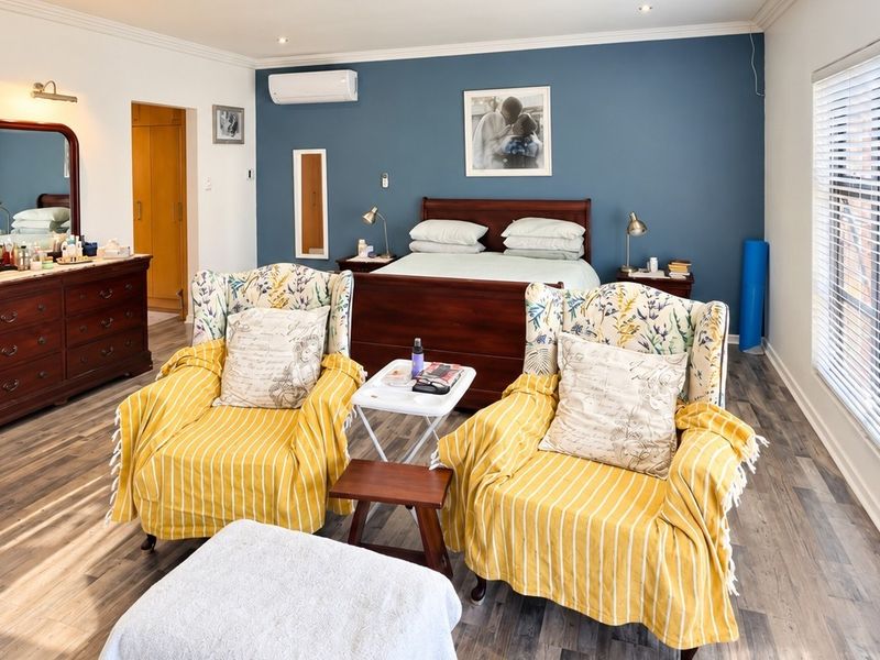 Spacious bedroom featuring a blue accent wall, split-system air conditioning, recessed lighting, and large windows with venetian blinds.
