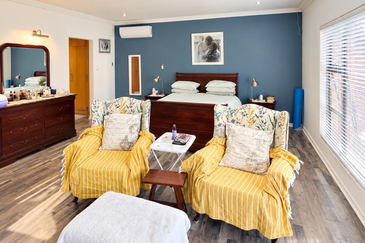 Spacious bedroom featuring a blue accent wall, split-system air conditioning, recessed lighting, and large windows with venetian blinds.
